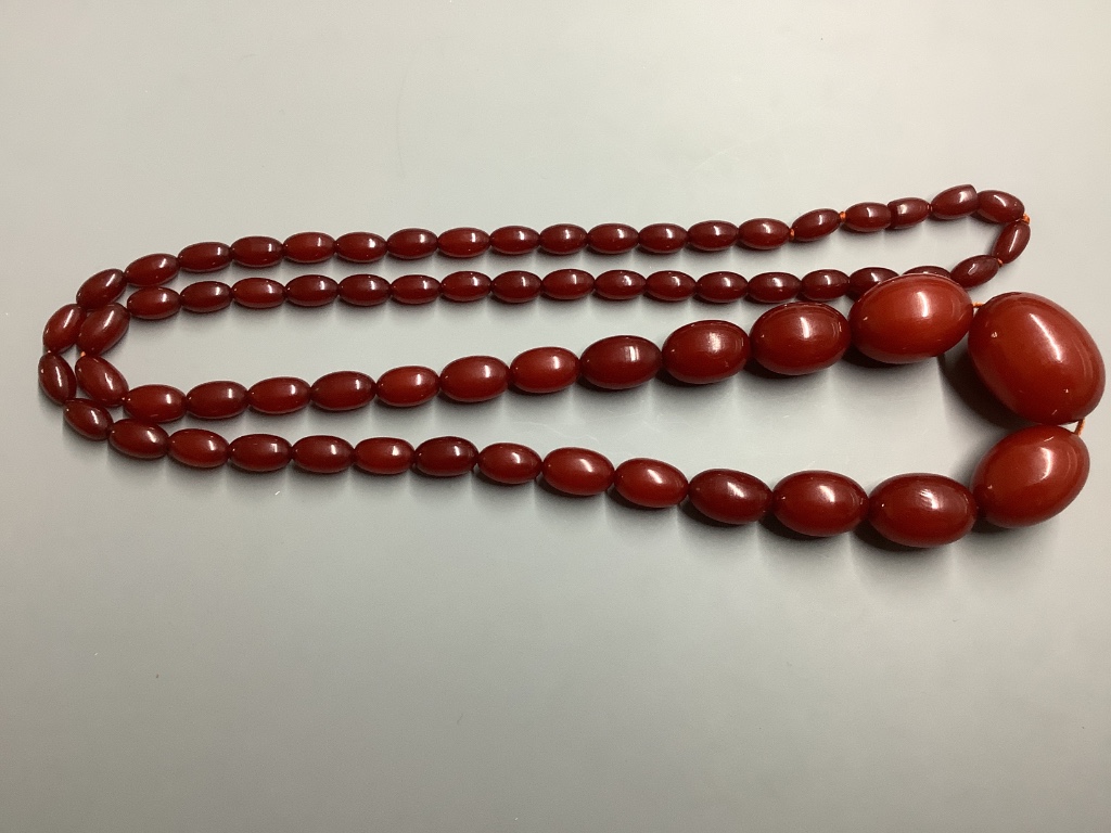 A single strand graduated oval simulated amber bead necklace, 100 cm, gross 91 grams.